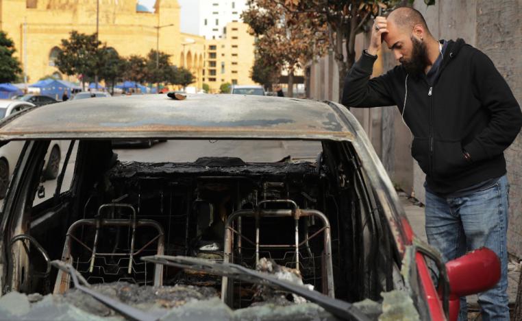 A man inspects the remains of a burned car that was destroyed during clashes between rival groups in Beirut