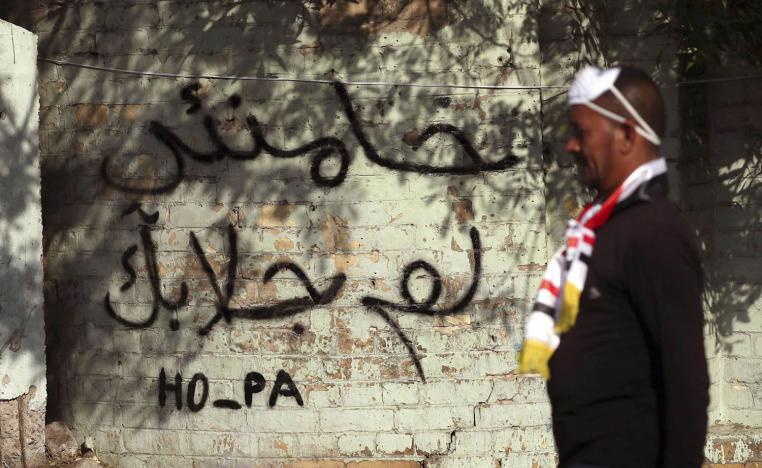 متظاهر عراقي يمر بالقرب من شعارات تنتقد خامنئي في بغداد