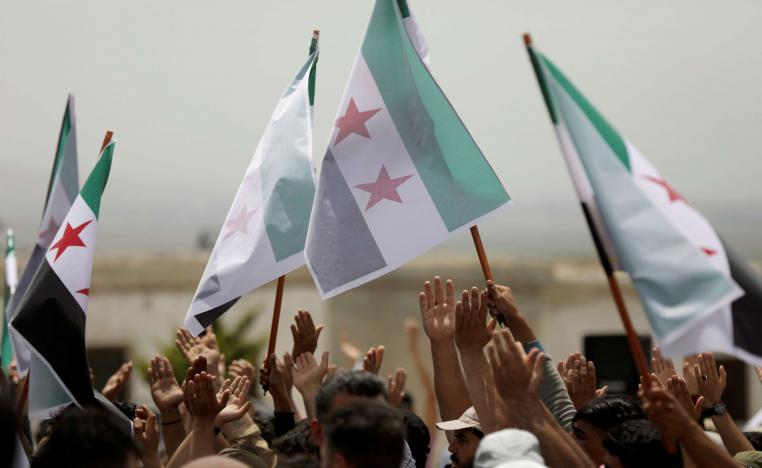 Syrian protesters raise the opposition flag in Idlib province