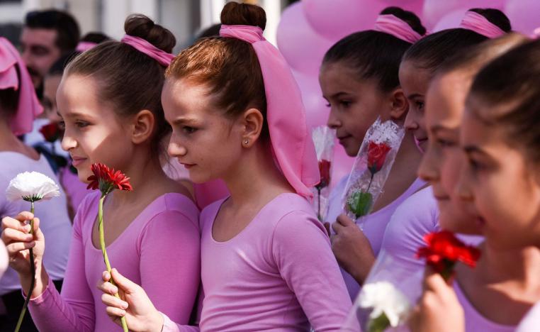 فتيات كوسوفيات يرتدين ملابس باليه ويحملن الورود ويغنين في تظاهرة للتوعية بسرطان الثدي