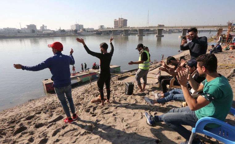 عراقيون يرقصون ويلوحون وهم يبحرون على ضفة نهر دجلة في العاصمة بغداد