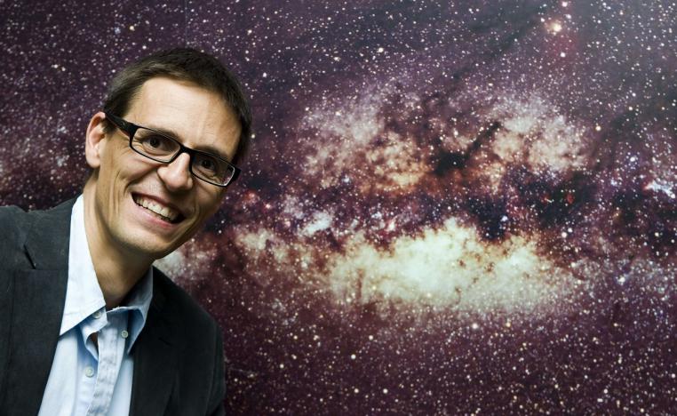 العالم السويسري ديدييه كويلو يقف أمام صورة لمجرة درب التبانة