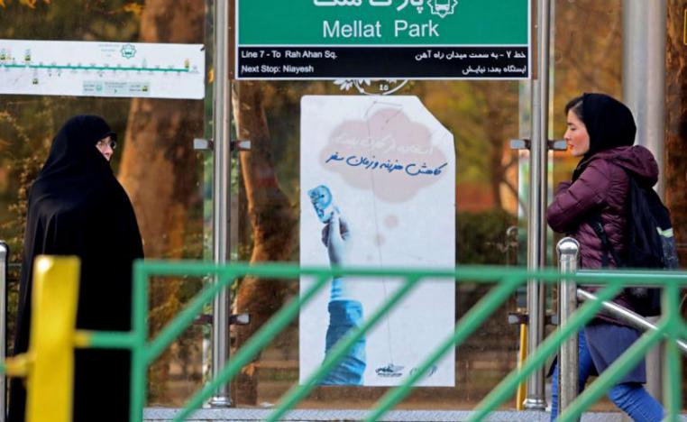 Iranian women walk past a bus station in Tehran