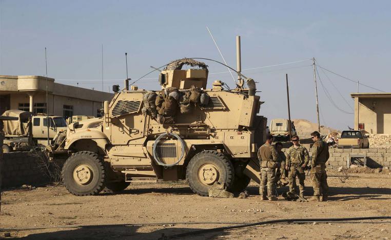 US Army soldiers stand outside their armoured vehicle on a joint base with Iraqi army south of Mosul