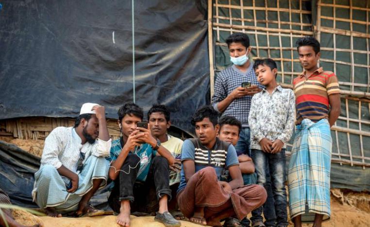 Rohingya refugees watch on a mobile phone a live feed of Myanmar's State Counselor Aung San Suu Kyi's appearance at the UN's International Court of Justice in the Hague