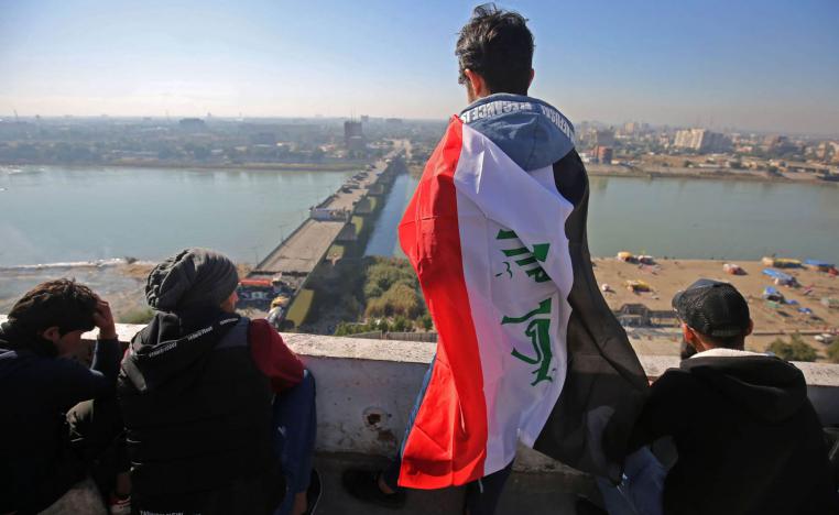 عراقي يتلفح بعلم فوق مبنى يطل على جسر الجمهورية وسط بغداد