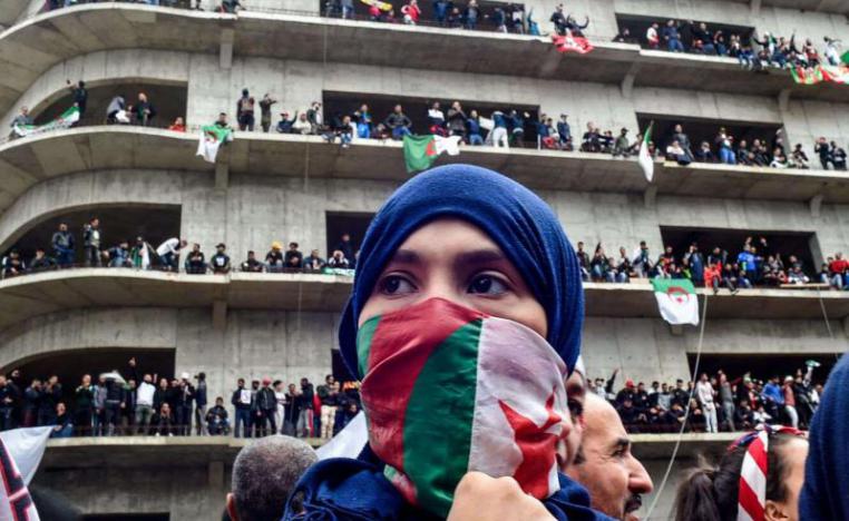  A woman covers her face with the national flag, as Algerian protesters demonstrate in the capital Algiers against ailing president's bid for a fifth term on March 8, 2019.