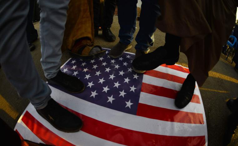 Iraqis step on a US national flag on December 30, 2019, during a demonstration to denounce the previous night's attacks