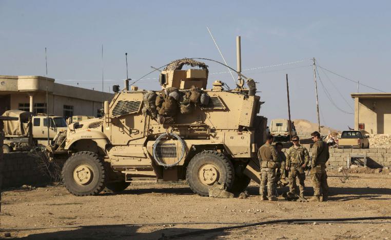 US Army soldiers stand outside their armored vehicle at a joint base in Iraq