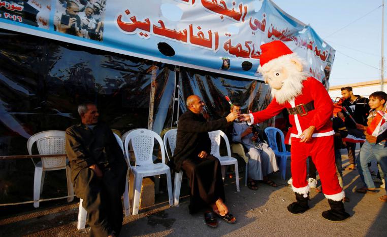 عراقي يرتدي بدلة بابا نويل يوزع الزهور على المحتجين في النجف