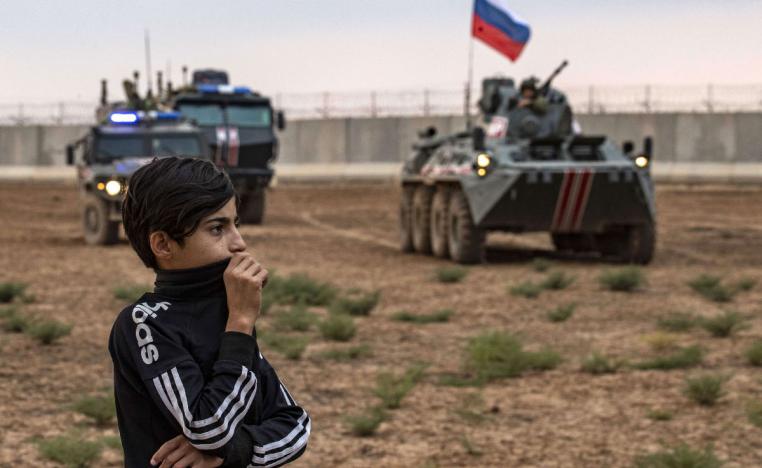 A young boy stands in front of Russian military vehicles in Syria's northeastern Hasakeh province