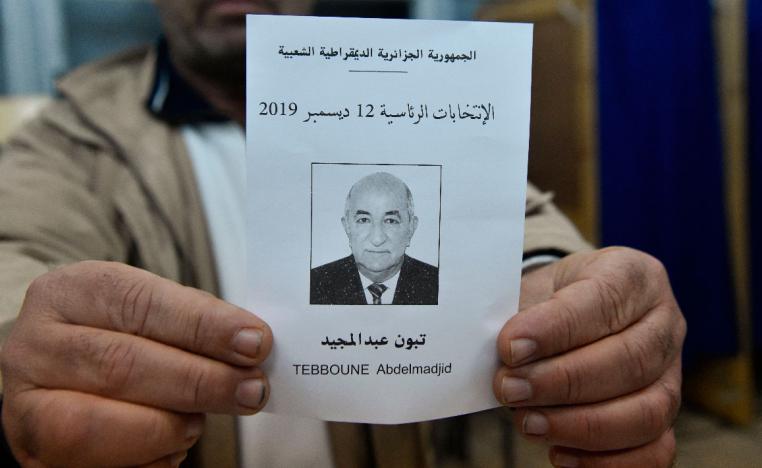 An election official displays a ballot paper of Algeria's presidential candidate Abdelmadjid Tebboune