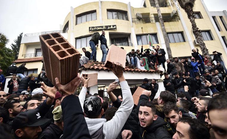 Algerian demonstrators carry bricks to build a wall at the entrance of the daira (sub-prefecture) of Tizi-Ouzou