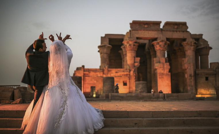 زوجان مصريان يرسمان بأصابعهما كلمة "حب" بالانكليزية أثناء زفافهما في معبد في اسوان