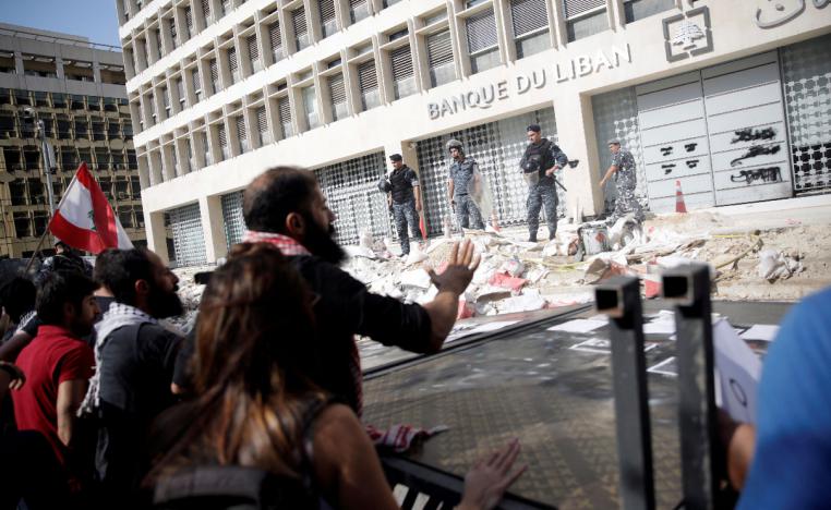 Police officers stand guard as protesters knocked down the fencing as they demonstrate outside of Lebanon Central Bank