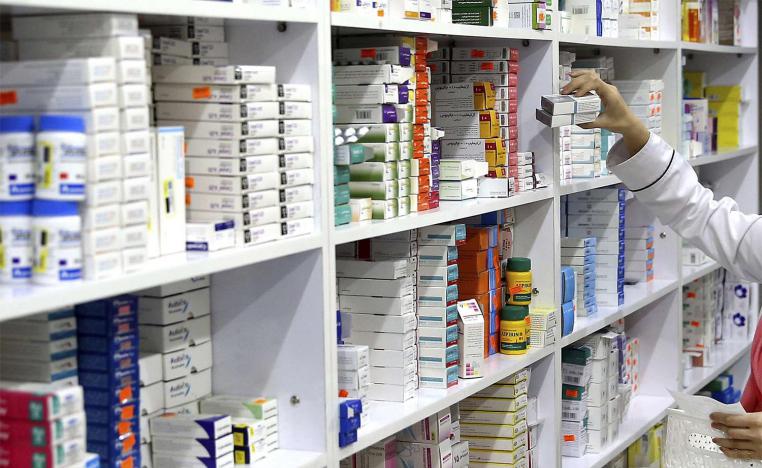 A drugstore employee reaches for medicine from shelf in Tehran
