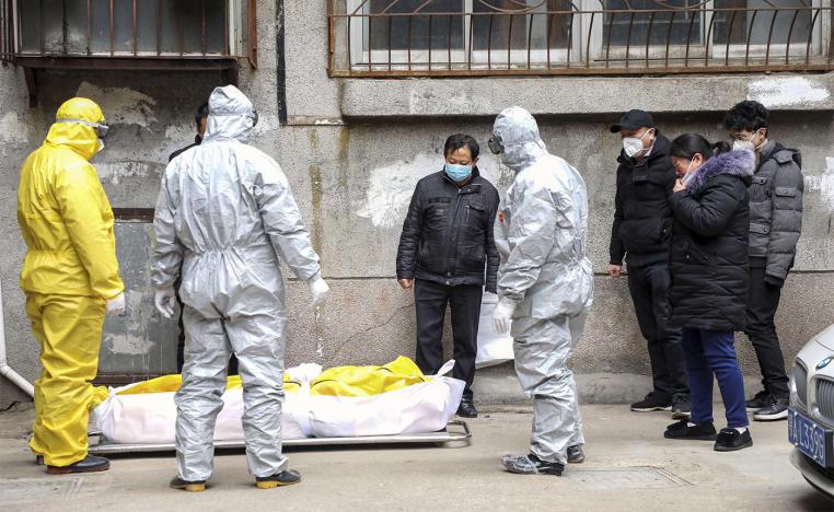 Funeral home workers remove the body of a person suspect to have died from a virus outbreak from a residential building in Wuhan 
