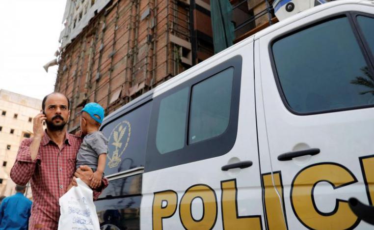 An Egyptian man carries his son as he walks past a police car in Cairo.