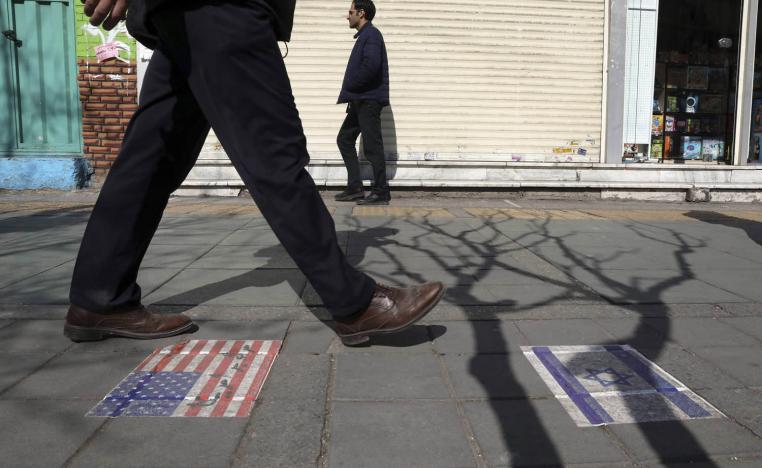 إيراني يمر على علمين لإسرائيل والولايات المتحدة