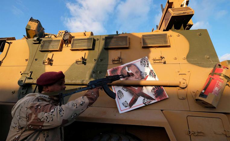 A member of Libyan National Army (LNA) commanded by Khalifa Haftar, points his gun to the image of Turkish President Tayyip Erdogan