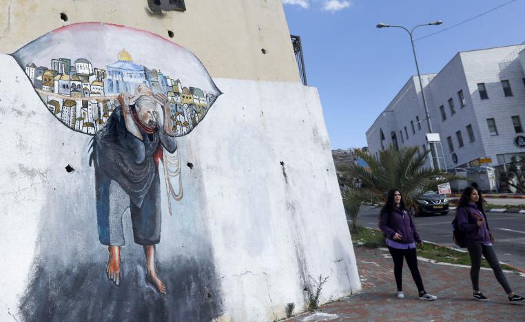 Schoolgirls walk past a mural in the Palestinian town of Umm al-Fahm inside Israel