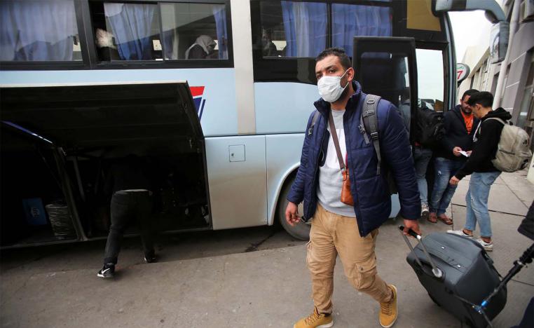 A man wearing a protective face mask walks with luggage, following the outbreak of coronavirus disease in Algiers