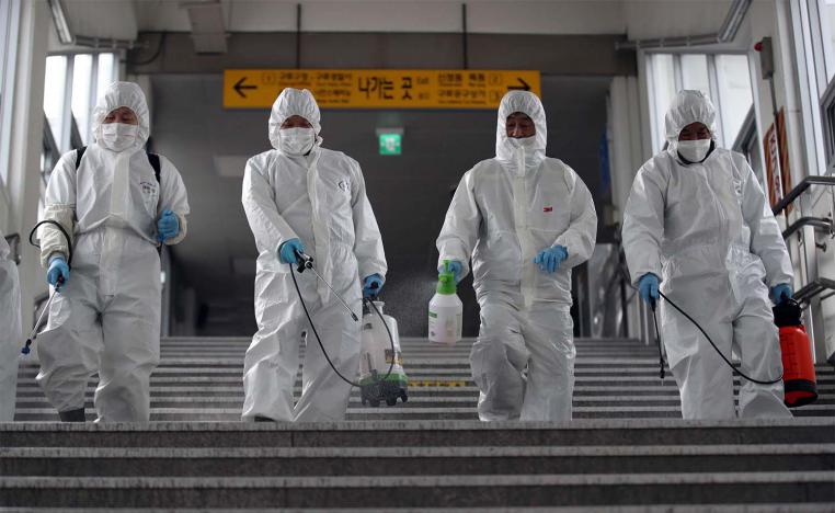 Workers wearing protective gear spray disinfectant to help prevent the spread of the COVID-19 coronavirus, at a subway station in Seoul 