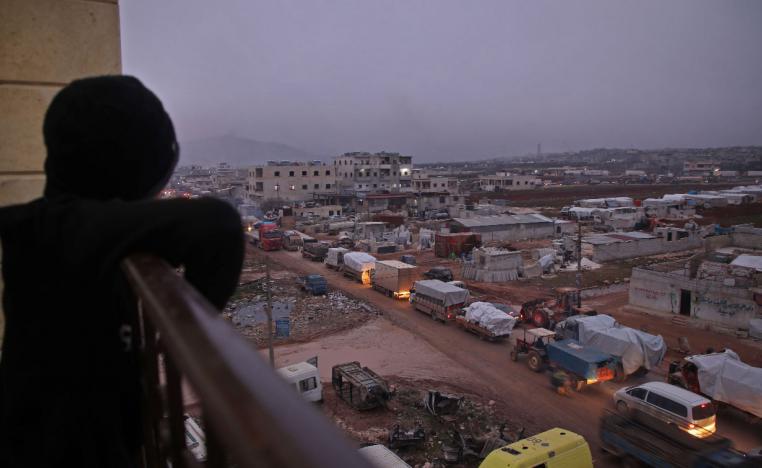 A child in the Syrian town of Dana, Idlib province, watches a large convoy of displaced people from a balcony