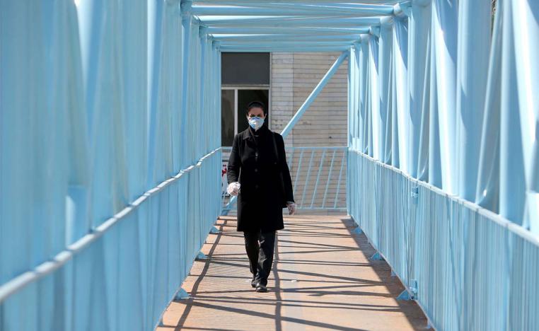 An Iranian pedestrian walks while wearing a protective mask in Tehran