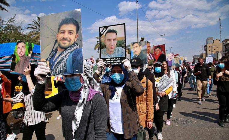 متظاهرون عراقيون يرفعون صور ضحايا العنف