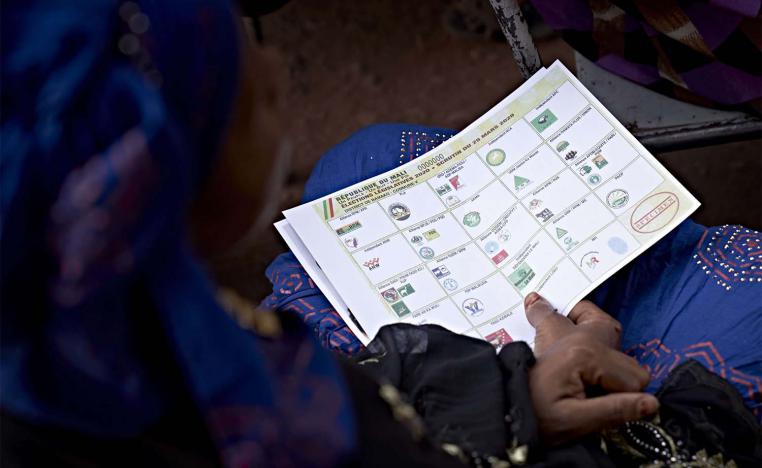 A Malian woman holds a polling paper during a meeting for the campaign of the parliamentary elections in Bamako