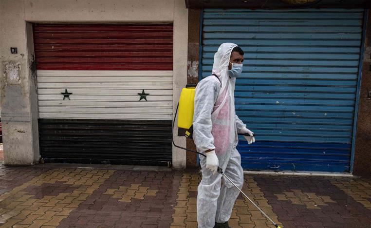 A member of disinfection units of the semi-autonomous Syrian Kurdish administration works on a street in the Kurdish-majority city of Qamishli in Syria