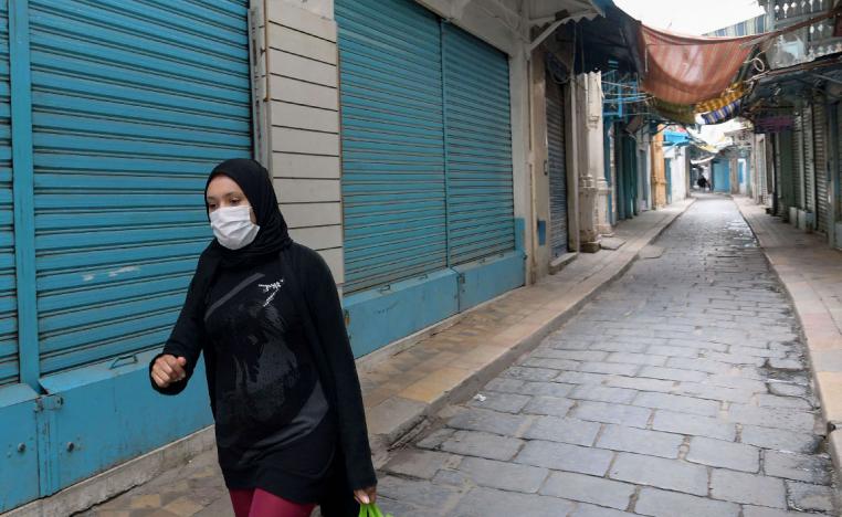 A Tunisian woman wearing a protective face mask walks through an alley in the souk of the Medina