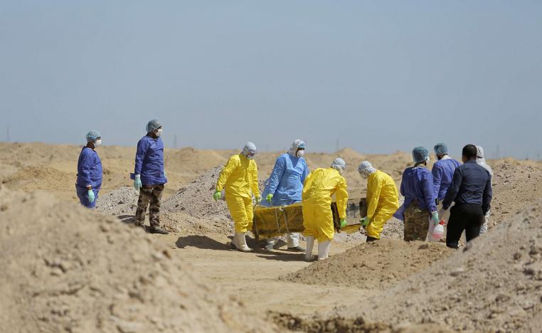 عمال وزارة الصحة العراقية يحملون تابوت شخص مات من فيروس كورونا 