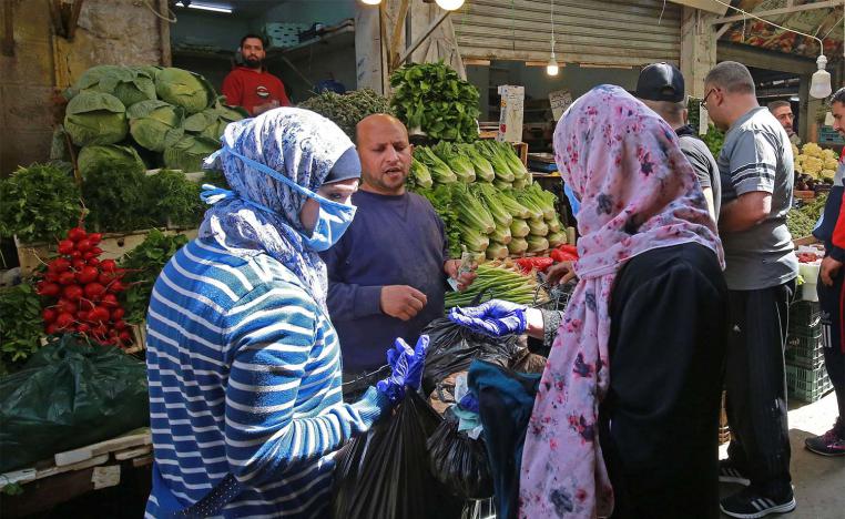 Women buy fresh vegetables at a market in Amman