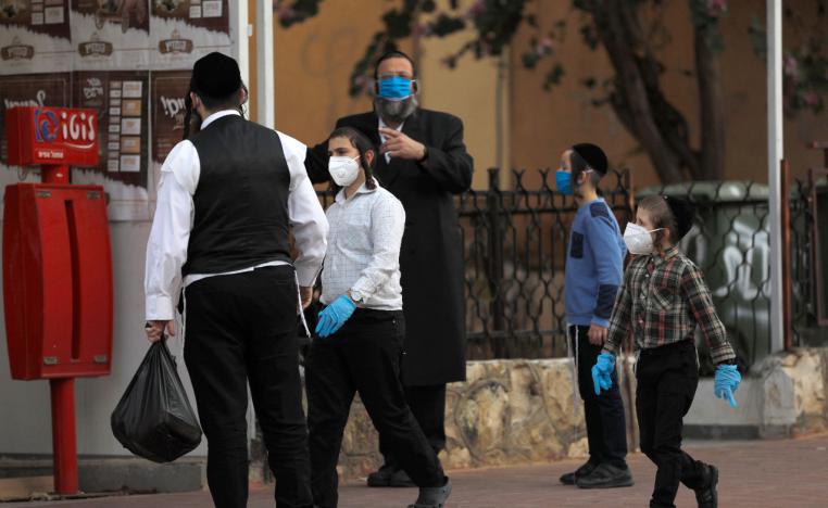 Ultra-Orthodox Jewish men and children wearing protective masks gather in a street