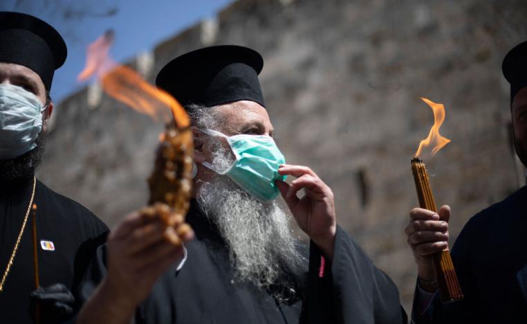 Orthodox clergymen hold candles lit from fire of the Church of the Holy Sepulchre