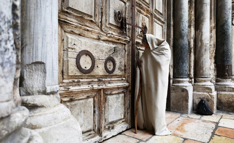 A man stands in front of the closed doors of the Church of the Holy Sepulchre