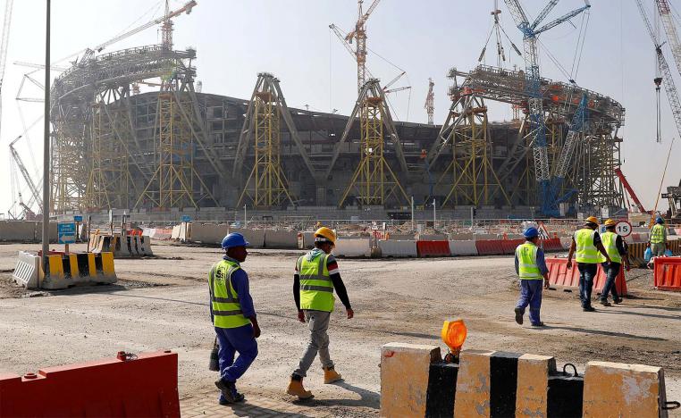 Workers walk towards the construction site of the Lusail stadium in Doha