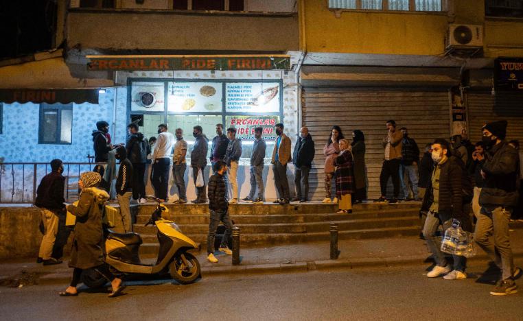 People queue at shops for food and supplies shortly before the curfew in Istanbul