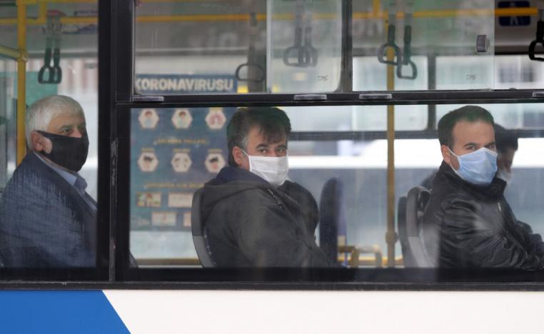 People wearing protective masks look on in a bus in Ankara