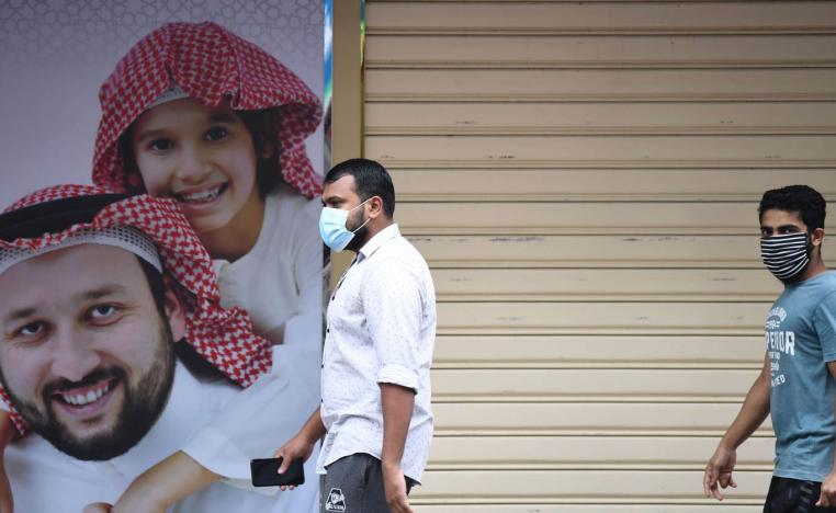 عمال اسيويون يمرون من أمام محال مغلقة في دبي