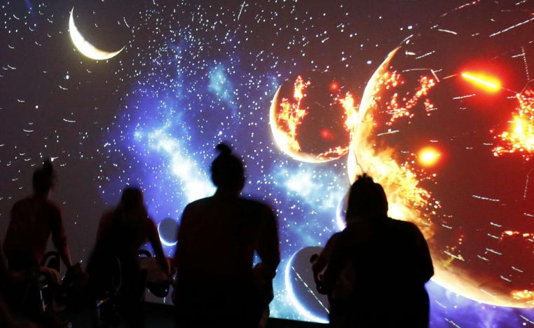 أشخاص ينظرون إلى صورة للنظام الشمسي تظهر على شاشة ضخمة في بروكلين في نيويورك