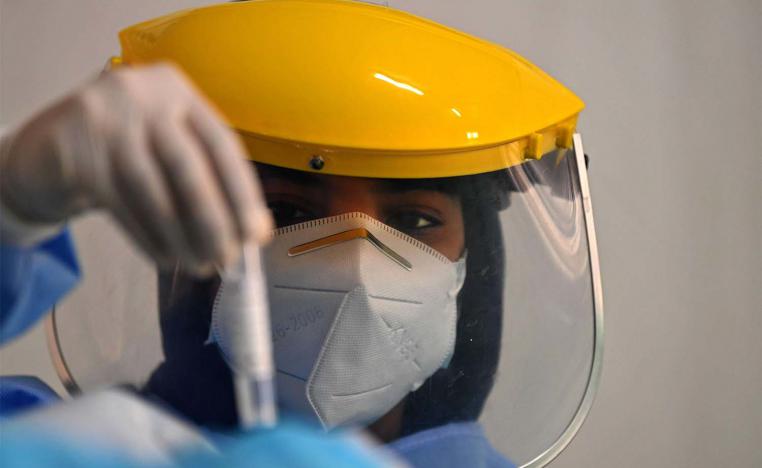 A health worker looks at a sample taken from a foreign worker to check for the novel coronavirus at a testing centre in the Al Quaz area of Dubai