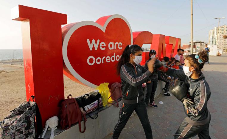 Palestinian girls participate in a boxing training session at the sidewalk of a beach 
