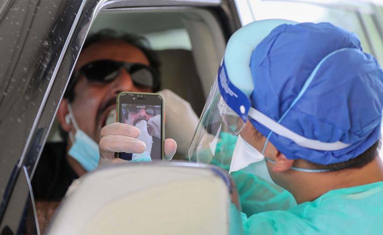 A health worker collects a swab sample from a man at a drive-thru testing service for COVID-19 coronavirus in Doha