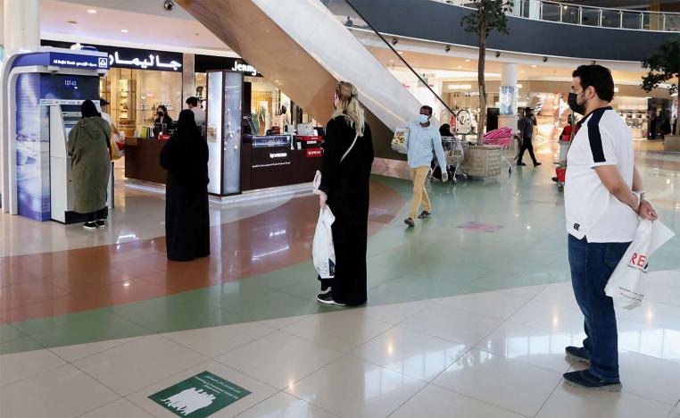 People line up while practicing social distancing to use an ATM at a shopping mall 