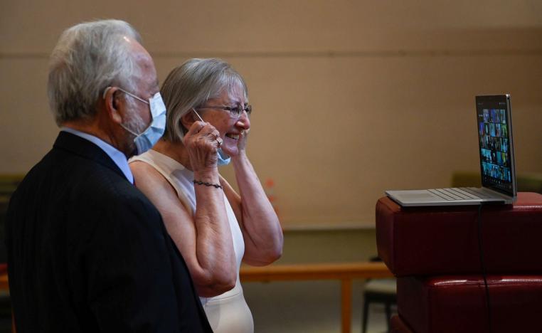 زوجان أميركيان يتحدثان مع أقاربهما عبر تطبيق زوم بعد حفل زفافهما في كنيسة بفرجينيا