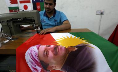 خياط كردي يعد علما مع صورة مسعود بارزاني