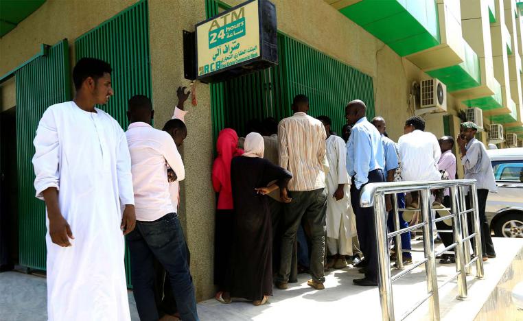 People queue to withdraw money from an automated teller machine, ATM, in Khartoum